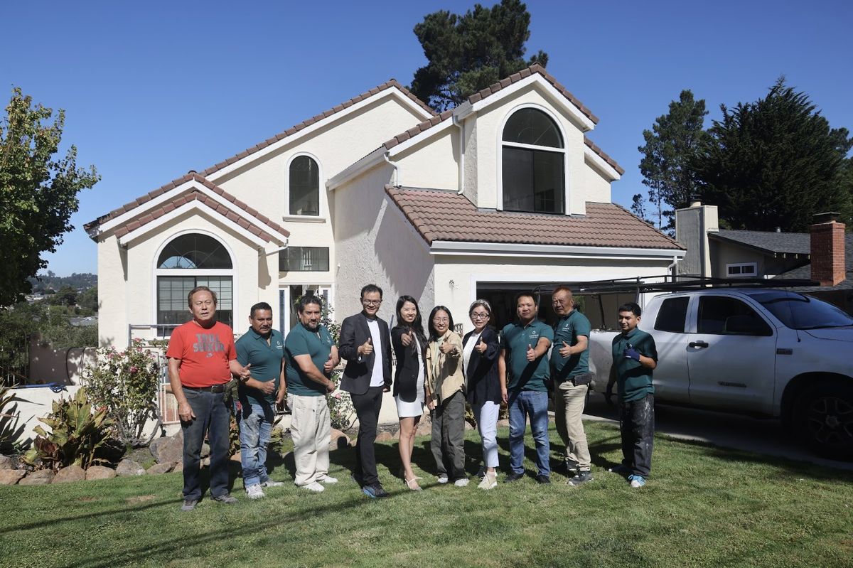 The Greenland team and construction crew in front of a two-story home
