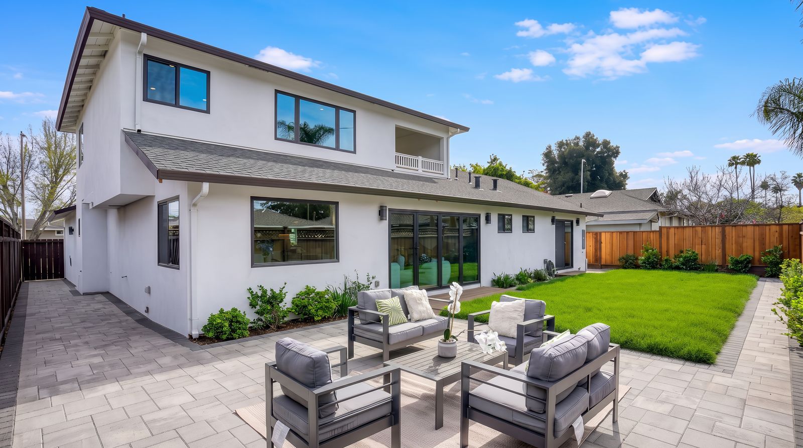Back of a new two-story white home with a paver patio, outdoor seating and a lawn