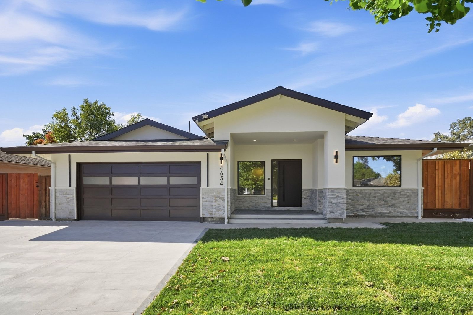 Single-story remodeled home with stone veneer, dark garage door and new lawn