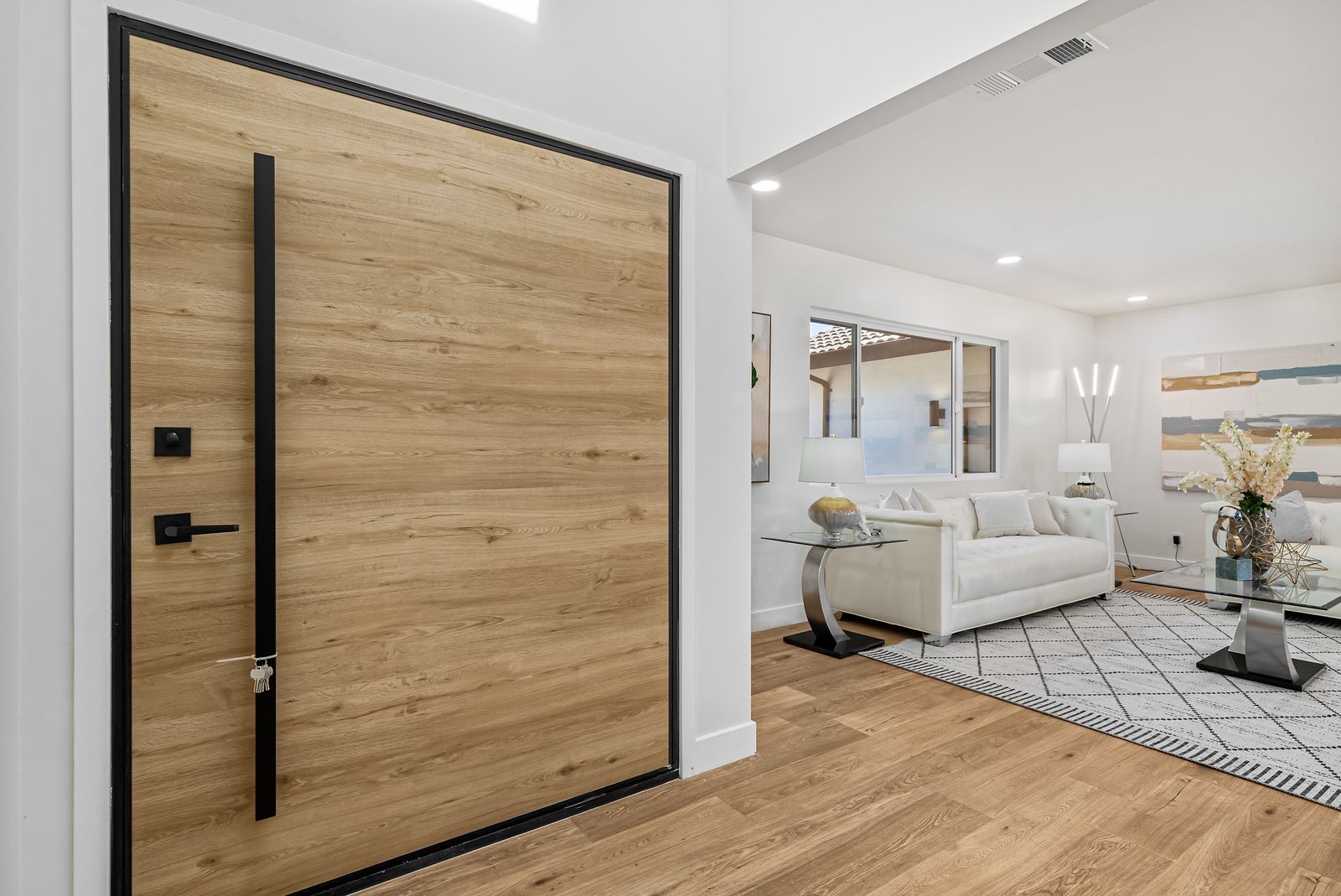 Oversized wood pivot front door opening to a living room